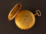 an old gold pocket watch on a black surface with a key
