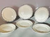 six assiettes blanches à bordure argentée sont disposées sur une table