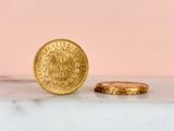 a gold coin sitting next to a gold coin on a marble surface