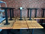 quatre tables en bois avec des pieds en métal et un mur de briques en arrière-plan