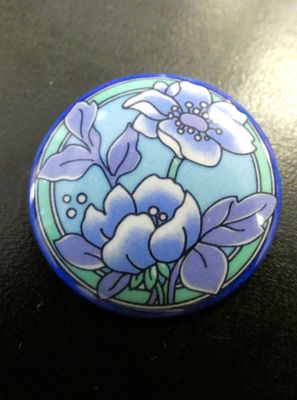 des fleurs violettes et bleues sur un fond bleu et vert, sur un bouton