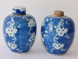 deux vases bleus ornés de fleurs blanches, posés sur une surface blanche
