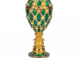 an image of a green and gold faber egg on a stand
