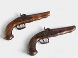 Deux pistolets anciens sont posés sur une surface blanche