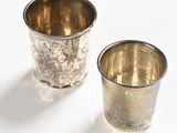 pair of silver cups on a white surface with a white background