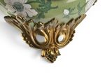 a green vase with flowers on it on a white surface
