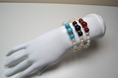 trois bracelets posés sur la main d'un mannequin, posée sur une table blanche
