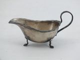 a silver plated gravy with a handle on a stand