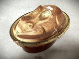 un bol marron orné d'un visage, posé sur une table