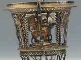 a silver vase with a horse on it on a table