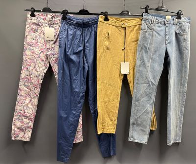 trois paires de jeans suspendues à un portant dans un magasin