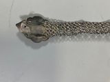 a silver bracelet with a fish on it on a white surface