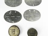 plusieurs vieilles étiquettes métalliques et une pièce de monnaie posées sur une surface blanche
