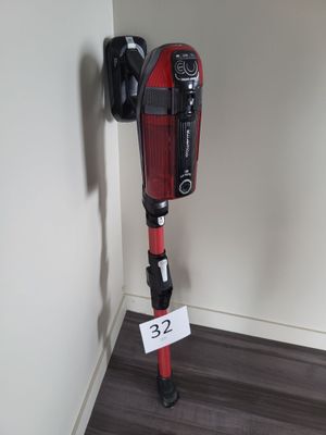 un aspirateur rouge et noir posé contre un mur blanc