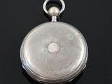 a silver pocket watch sitting on a black surface