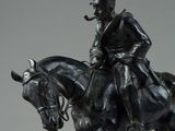bronze statue of a man on a horse with a pipe in his mouth