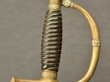an old sword with a gold handle on a wooden stand