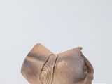 un petit objet en bronze posé sur une surface blanche