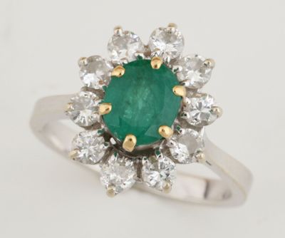 gros plan d'une bague avec une pierre verte entourée de diamants blancs