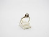 une bague en or blanc et diamants posée sur un bloc de marbre blanc