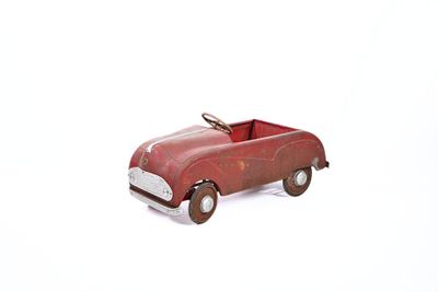 a red toy car that is sitting on a white surface