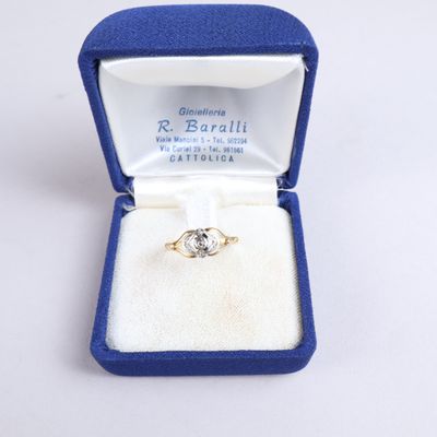 une photo d'une bague en diamant dans un écrin bleu posé sur une surface blanche