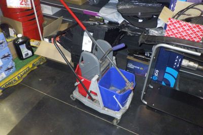 un chariot sur lequel se trouvent une serpillière et des seaux, dans un magasin