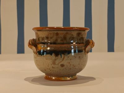 a brown and blue vase sitting on a white table