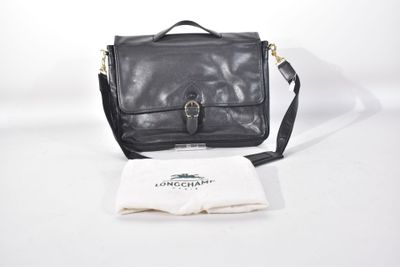 Le petit sac noir est posé sur la table, à côté d'une nappe blanche.