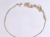 a close up of a gold chain bracelet on a white surface