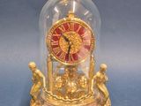 une horloge placée sous un dôme en verre, posée sur une table