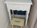 une petite table blanche avec un tabouret en bois dans un coin de la pièce