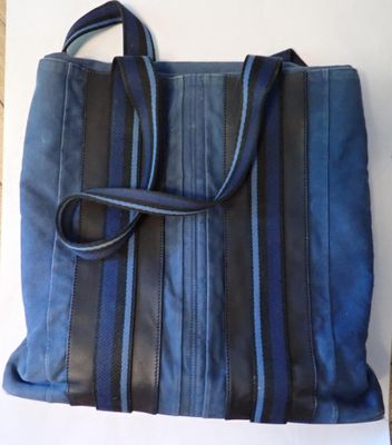 sac à main bleu et noir posé sur une surface blanche