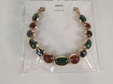 Le bracelet est composé de pierres dorées, vertes et rouges.