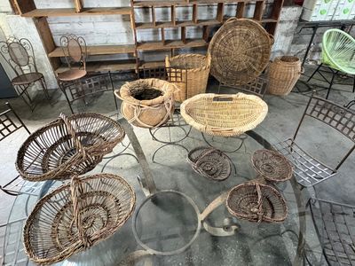 Plusieurs chaises et tables en osier sont disposées autour d'une table au plateau en verre