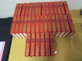 many red books stacked on top of each other on a table