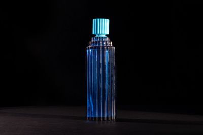 a blue bottle of perfume sitting on top of a black table