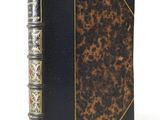 an old book with a black cover and gold trim