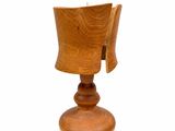 une petite tasse en bois posée sur un socle, sur une surface blanche