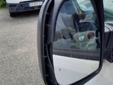 cars parked in a parking lot with a dog in the rear view mirror