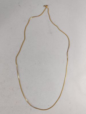 a gold plated necklace on a white surface