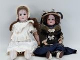 two dolls sitting next to each other on the floor