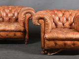paire de fauteuils en cuir avec accoudoirs capitonnés et repose-pieds, sur un socle noir