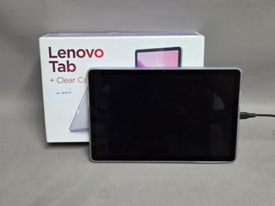 une tablette posée sur une table à côté d'un carton contenant des tablettes Lenovo