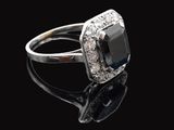 gros plan d'une bague avec une pierre noire entourée de diamants blancs