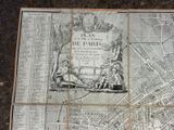 an old map of paris on a table with a map of the city
