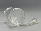 un petit bocal en verre avec un bouchon en verre à côté