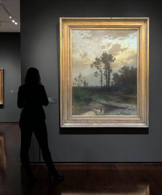 woman standing in front of a painting in a museum looking at it