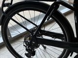 a black bike parked on the sidewalk next to a parking meter