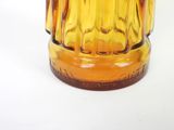 a yellow glass vase with a brown base on a white surface